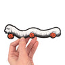 A hand holding a die cut sticker of a millipede in a ghost costumer carrying three jack 'o lantern candy pails. 