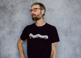 A model wearing a black t-shirt with a hand drawn illustration of a millipede in a ghost costume carrying jack'o lantern candy pails. 