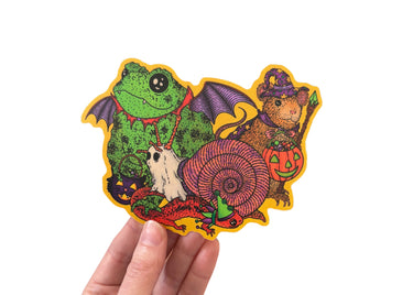 A hand holding a sticker featuring various animals trick or treating in retro style costumes for halloween. 